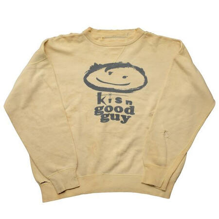 A beige sweater with a cartoon smile on it that reads "kisn good guy"